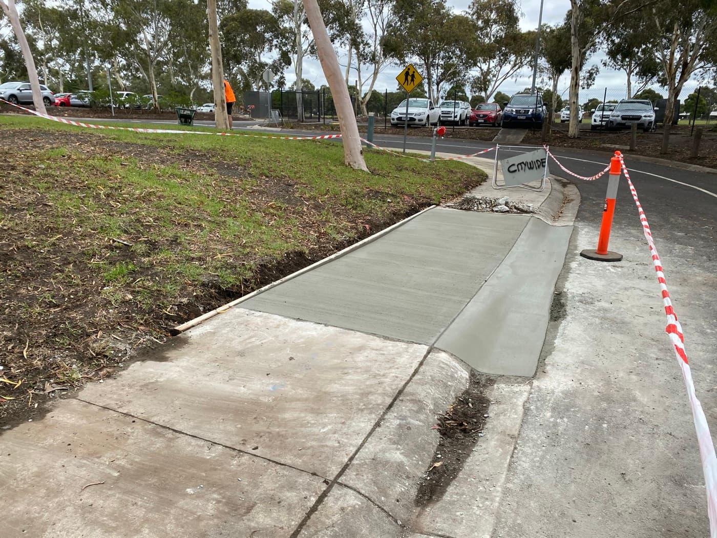 Freshly poured footpath repair with spoon drain edge outside the council offices