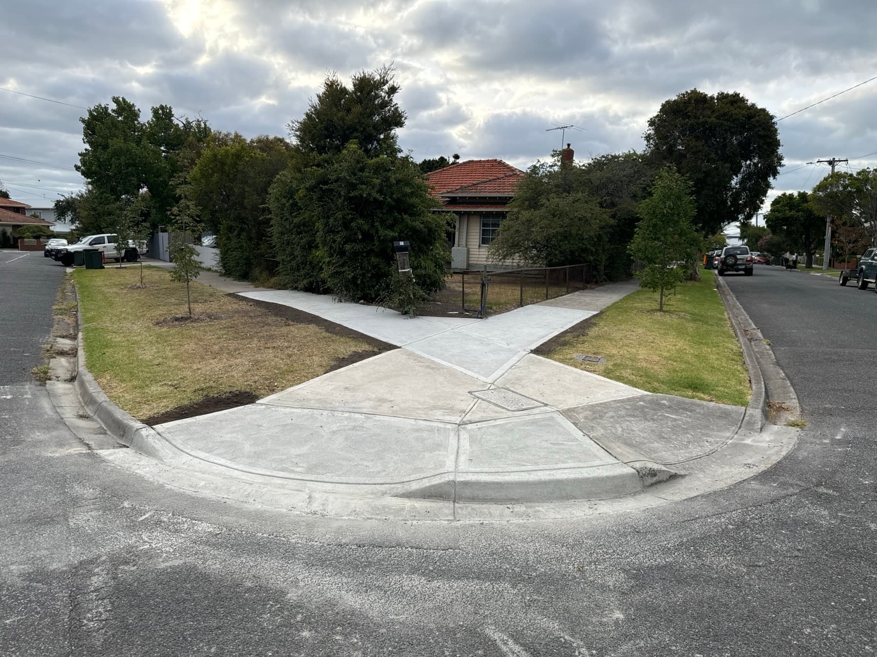 Two finished concrete vehicle crossings meeting a new kerb return on a corner block